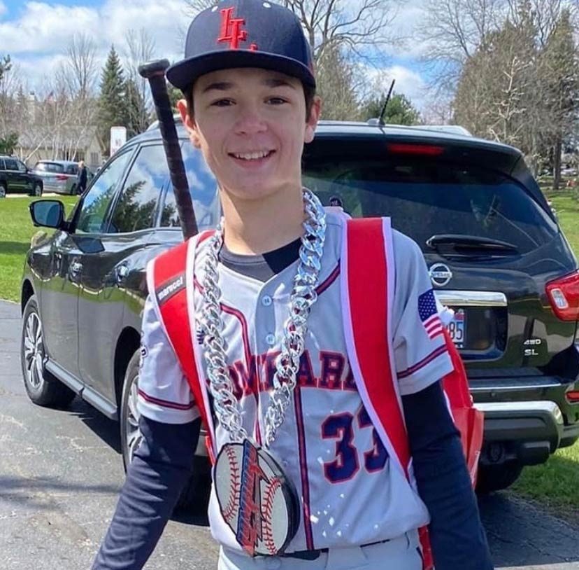 Baseball player wearing a chain and team backpack.